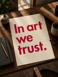 Typografie-Poster mit rotem Schriftzug „In art we trust.“ auf hellem Hintergrund.