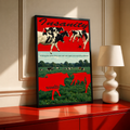 Red cow silhouettes and black and white cattle above a green pasture; black framed print on a red cabinet