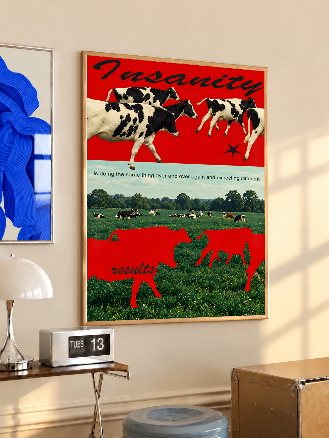Red cow silhouettes and black and white cattle above a green pasture; oak framed print in a desk setting