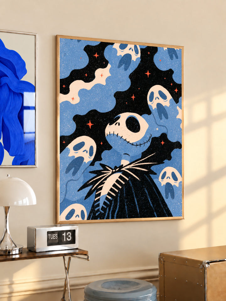 Jack Skellington surrounded by blue ghosts, cream clouds and tiny orange stars on black in a light wood frame on a sunlit office wall beside a desk