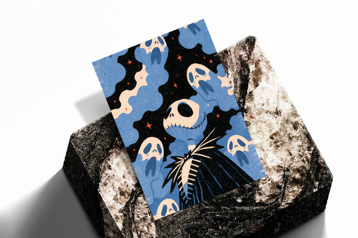 Jack Skellington surrounded by blue ghosts, cream clouds and tiny orange stars on black as an unframed print resting at an angle on a dark stone display