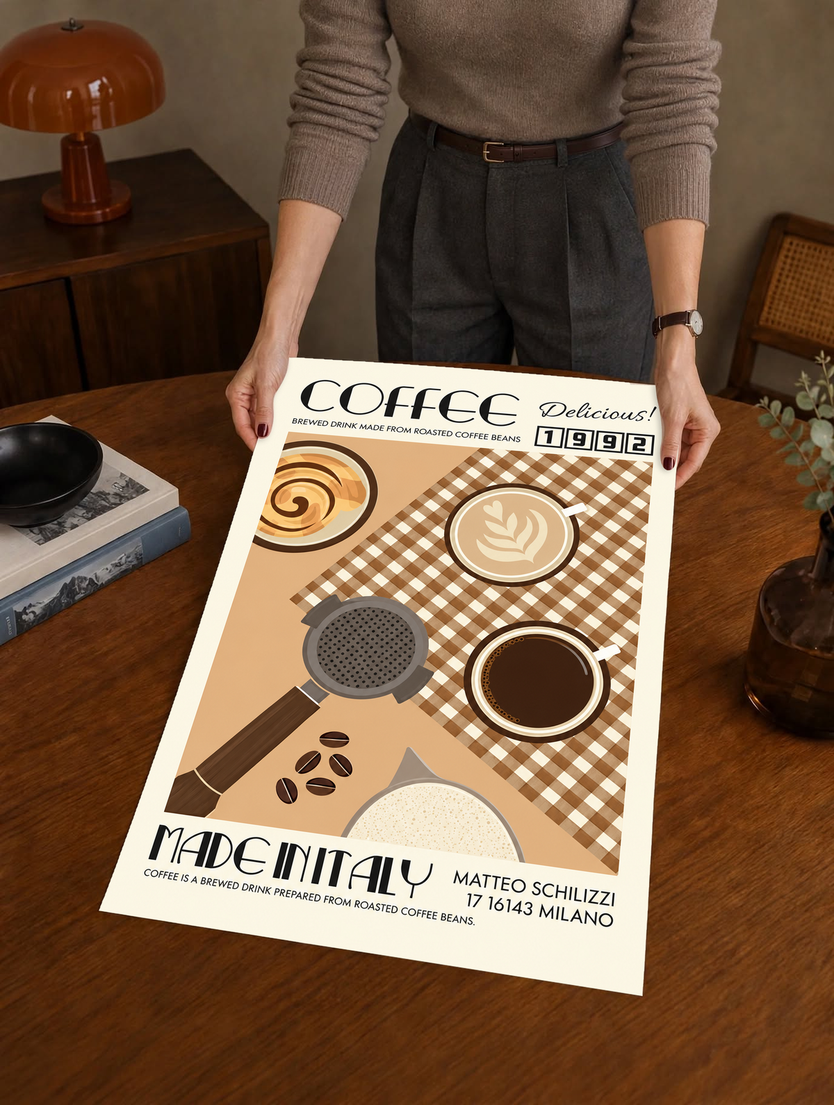 Mockup eines ungerahmten Drucks, von einer Person in einem warmen Innenraum gehalten: Italienisches Kaffeemotiv mit Tassen von oben, Siebträger, braunem Karo, cremefarbenem Rand sowie COFFEE, 1992 und MADE IN ITALY.