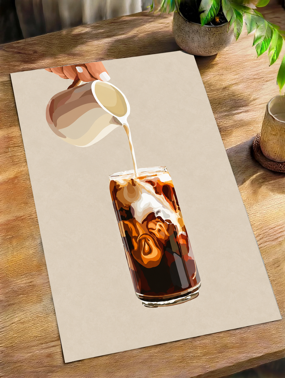 Mockup eines ungerahmten Posters auf einem Holztisch im Tageslicht: Eiskaffeeillustration mit einer Hand, die Milch aus einem gestreiften Kännchen in ein hohes Glas gießt, und cremefarbenen Karamellwirbeln auf Beige.