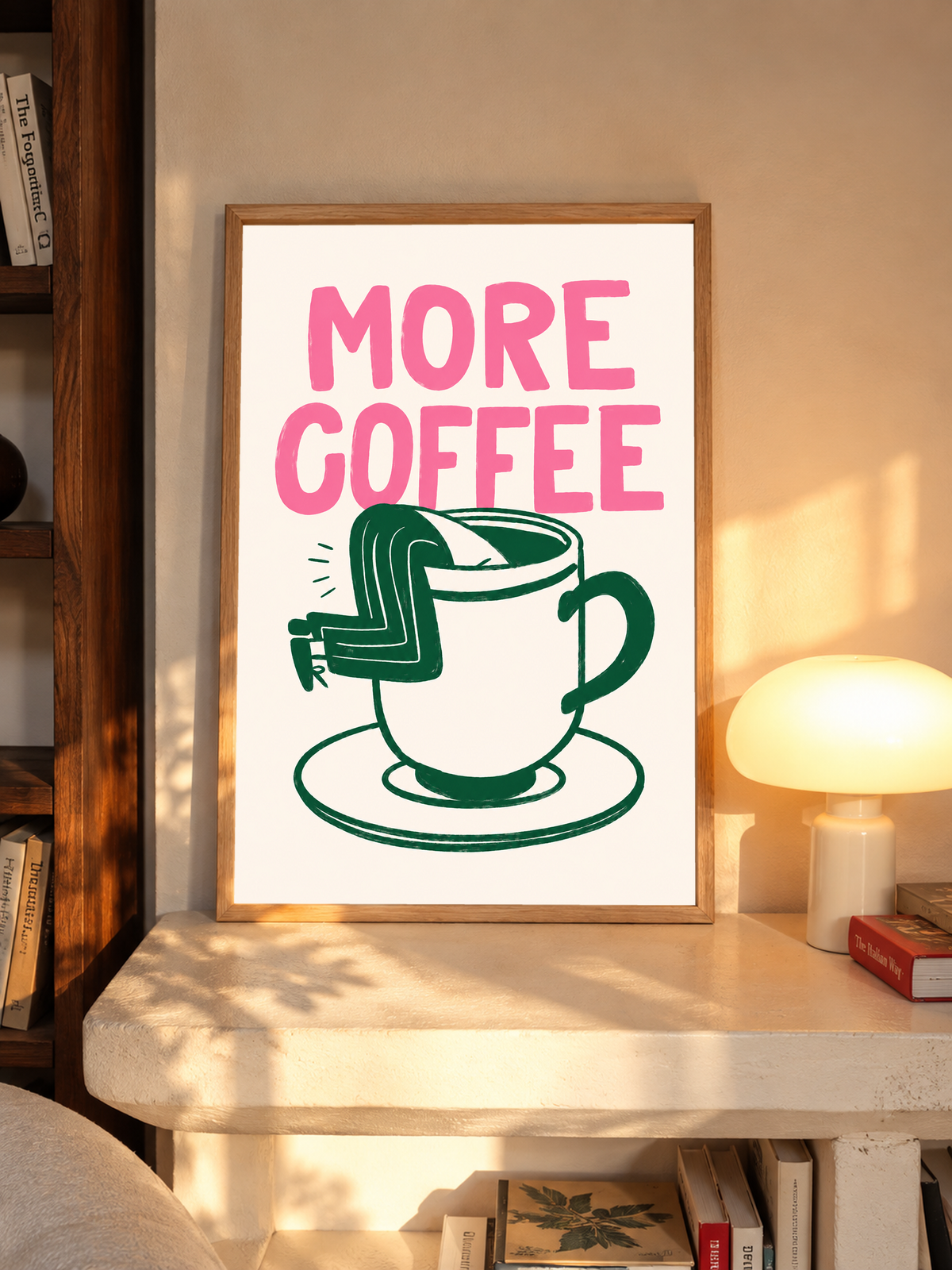 Mockup im Eichenrahmen auf einem Regal neben einer leuchtenden Tischlampe: Großes rosa MORE COFFEE über einer grün gezeichneten Tasse mit Untertasse und einem Beinpaar über dem Rand auf Creme.