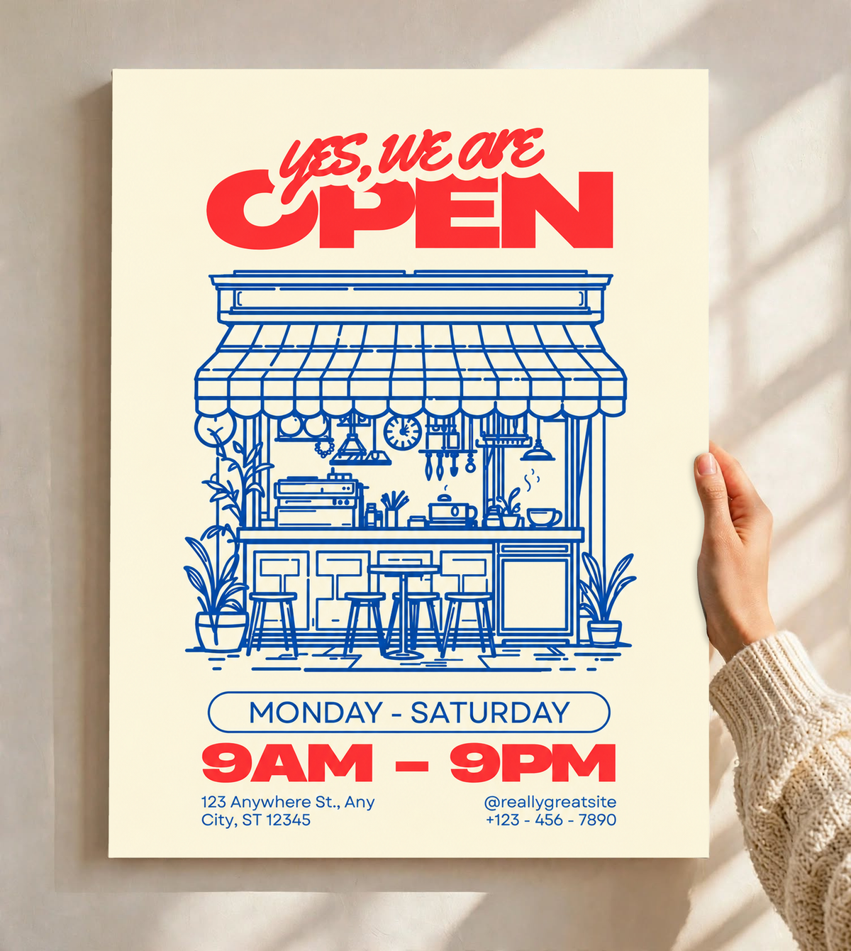 Ambientazione del poster senza cornice tenuto davanti a una parete chiara con luce dalla finestra: Yes, we are OPEN in rosso sopra un bar disegnato in blu con tenda, bancone, sgabelli, piante, orari e contatti di esempio su fondo crema.