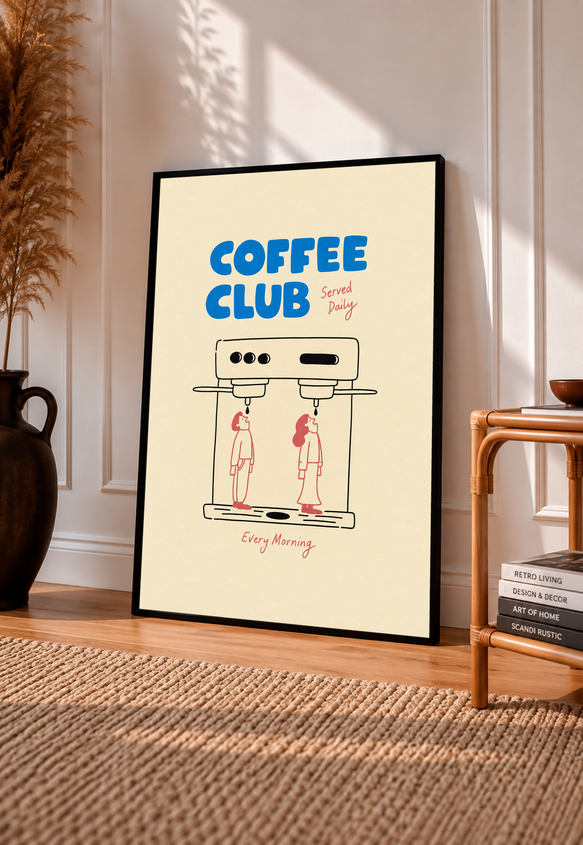 Blaues Coffee Club-Motiv mit schwarz gezeichneter Espressomaschine, zwei korallroten Figuren, roter Schrift und cremefarbenem Hintergrund. Im schwarzen Rahmen an einer sonnigen Wand, neben Holzstuhl und gewebtem Teppich.