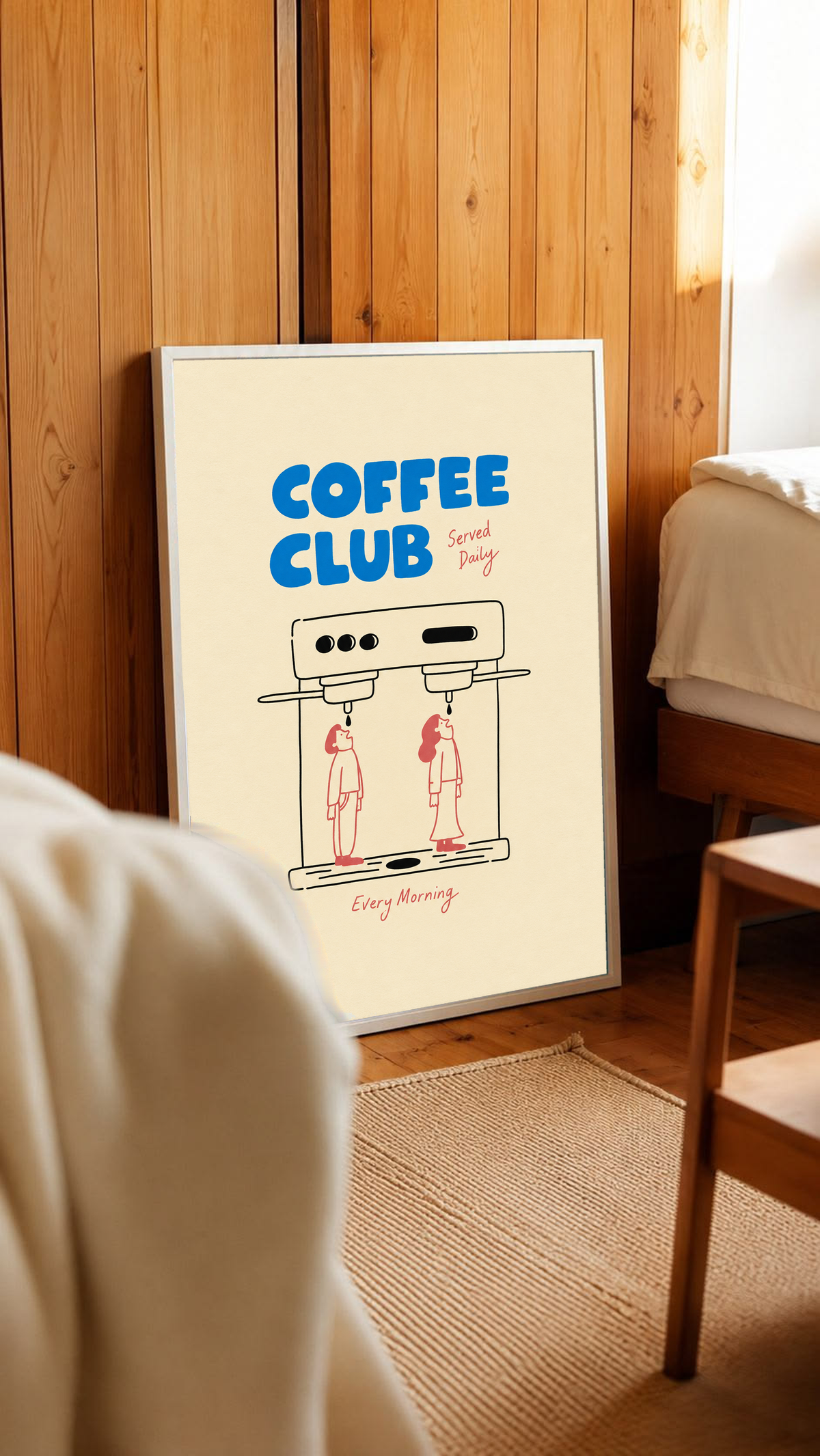 Blaues Coffee Club-Motiv mit schwarz gezeichneter Espressomaschine, zwei korallroten Figuren, roter Schrift und cremefarbenem Hintergrund. Im weißen Rahmen an einer holzvertäfelten Wand, neben Bett und Stuhl.