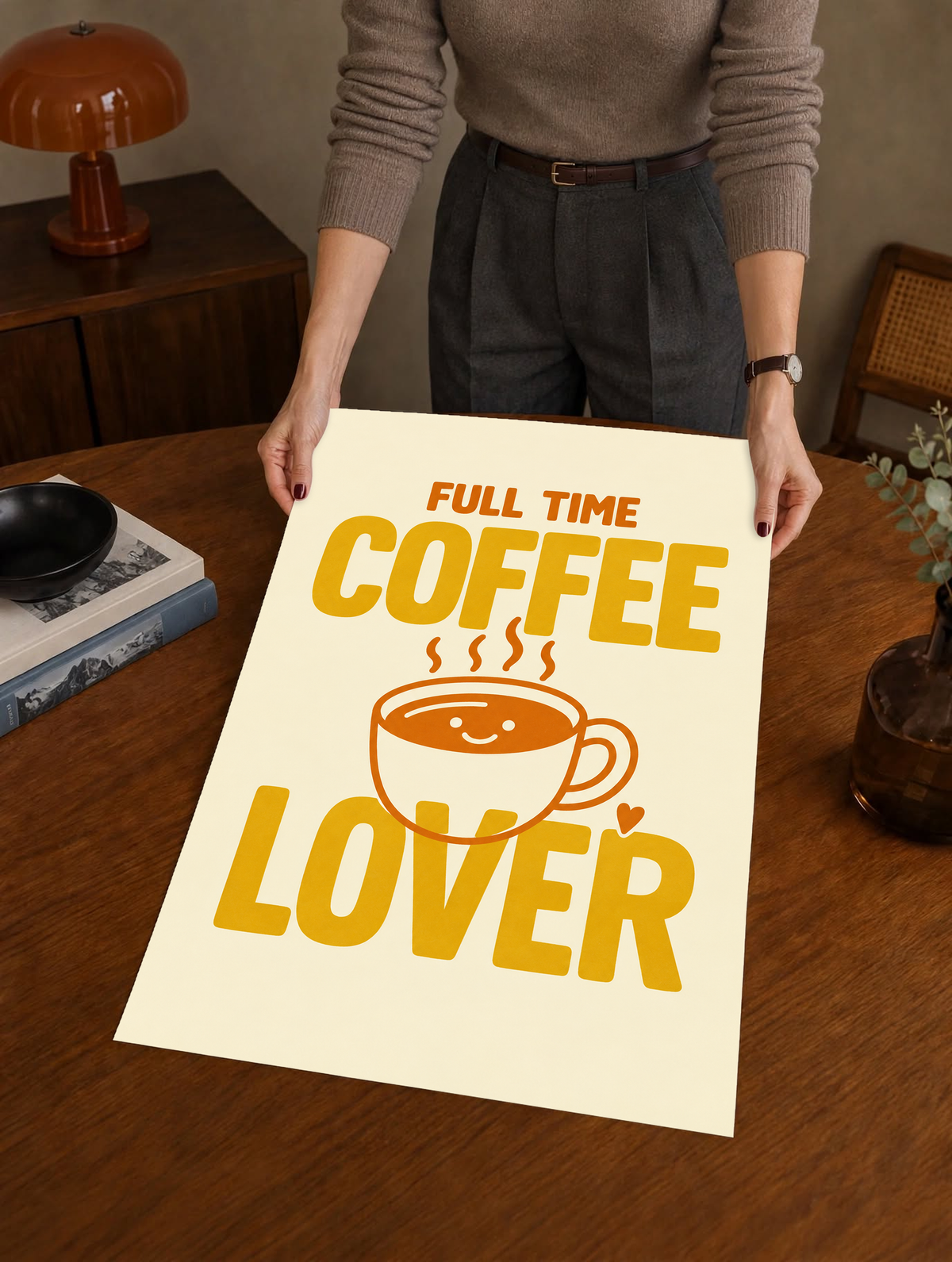 Full Time Coffee Lover-Motiv mit goldgelber Schrift, orangefarbener lächelnder Kaffeetasse, Dampf und kleinem Herz auf Creme. Ungerahmtes Poster, über einem Holztisch neben einem Plattenspieler gehalten.