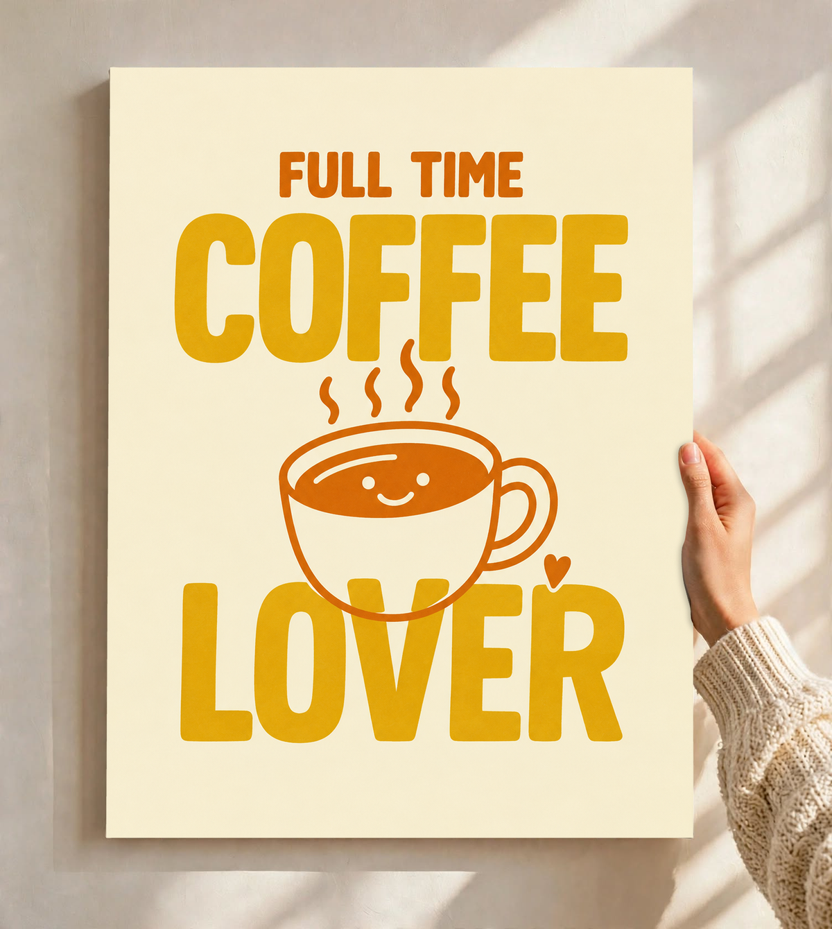 Full Time Coffee Lover-Motiv mit goldgelber Schrift, orangefarbener lächelnder Kaffeetasse, Dampf und kleinem Herz auf Creme. Ungerahmtes Poster, vor einer hellen Wand mit Fensterschatten gehalten.