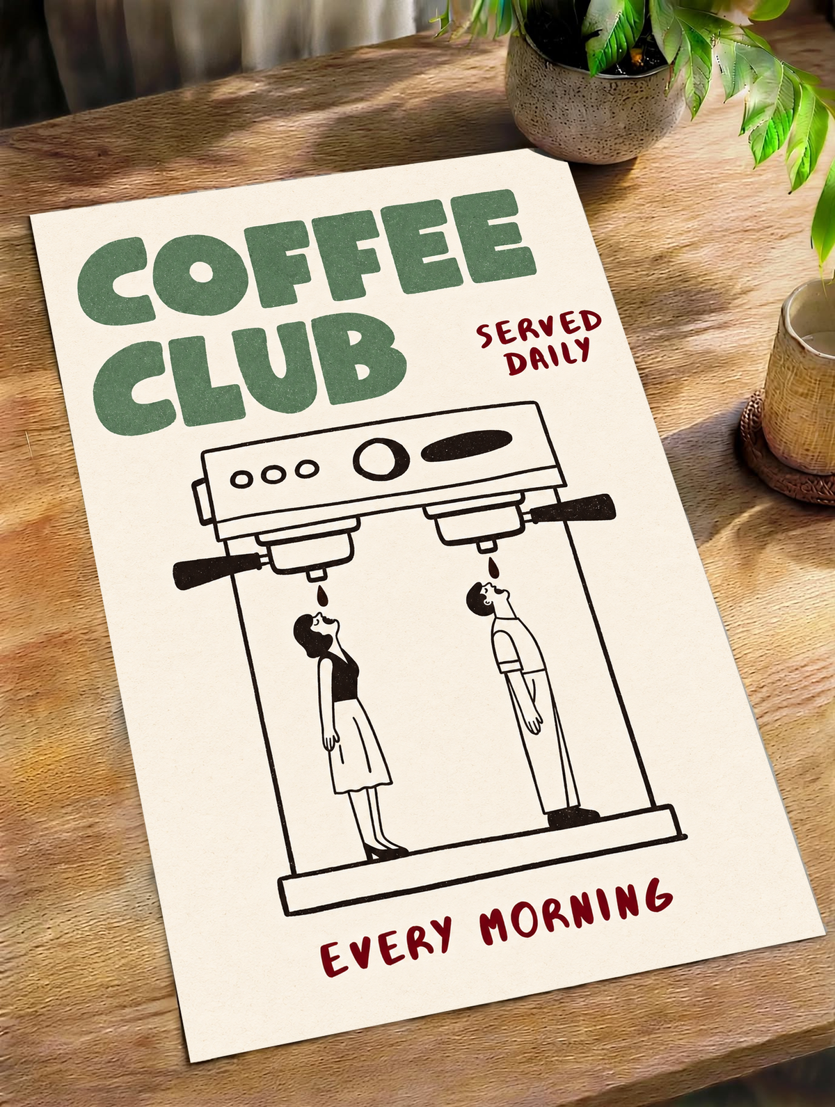 Ilustración Coffee Club verde con cafetera espresso doble negra, dos pequeñas figuras negras, palabras burdeos y fondo crema cálido. Póster sin marco en diagonal sobre una mesa de madera, junto a una planta y una taza.