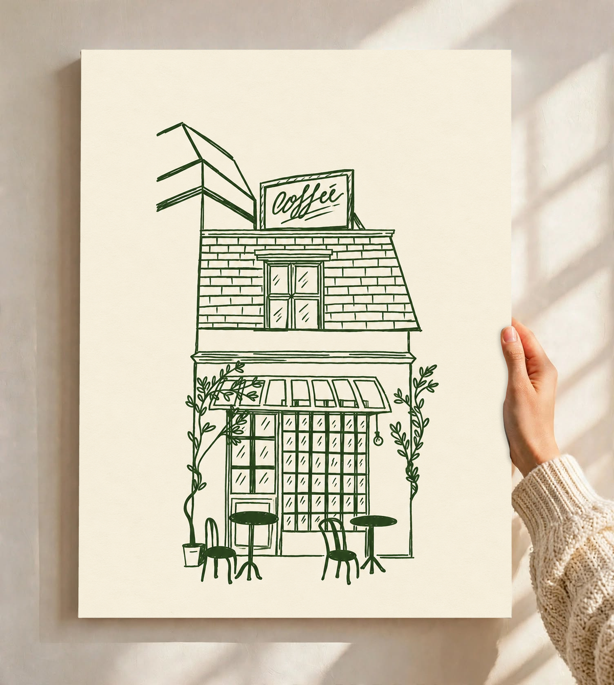 Kleines Kaffeehaus in dunkelgrünen Linien auf Creme, mit Dachschild, gestreifter Markise, Kletterpflanzen sowie Tischen und Stühlen im Freien, als ungerahmtes Poster vor einer hellen Wand mit weichen Fensterschatten gehalten.