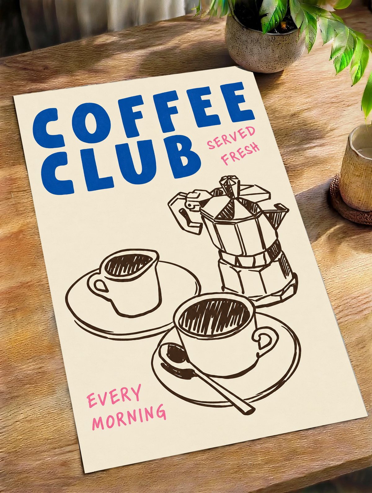 Blauer Schriftzug „Coffee Club“ mit rosa „Served Fresh“ und „Every Morning“ über einer braunen Mokkakanne und zwei Tassen auf Creme, als loses Poster schräg auf einem Holztisch neben Topfpflanzen liegend.