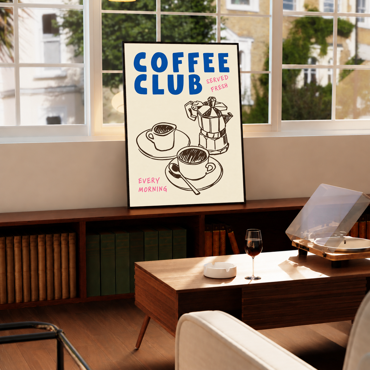 Blauer Schriftzug „Coffee Club“ mit rosa „Served Fresh“ und „Every Morning“ über einer braunen Mokkakanne und zwei Tassen auf Creme, in einem schwarzen Rahmen unter einem großen Fenster, nahe einem niedrigen Holztisch mit geöffnetem Plattenspieler.