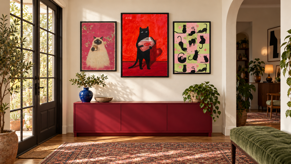 Three colourful cat art prints above a red sideboard in a sunlit room