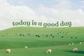 Grüne Schrift 'today is a good day' über Weiden mit Schafen, kleinen Rindern und hellem Wolkenhimmel. Ungerahmte horizontale Bildvorschau mit der vollständigen Komposition.