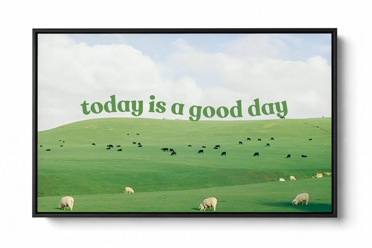 Grüne Schrift 'today is a good day' über Weiden mit Schafen, kleinen Rindern und hellem Wolkenhimmel. Dunkler Schattenfugenrahmen vor einem weißen Hintergrund mit weichem Schatten.