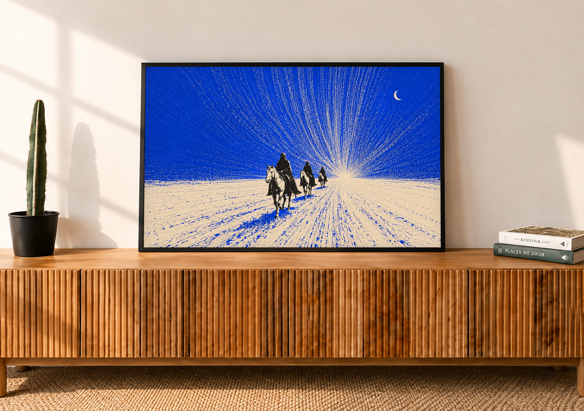 Tres jinetes oscuros se acercan sobre terreno crema bajo un cielo cobalto, una luna creciente y trazos finos radiantes. Marco negro sobre un aparador de madera con listones, junto a un cactus en maceta y libros.