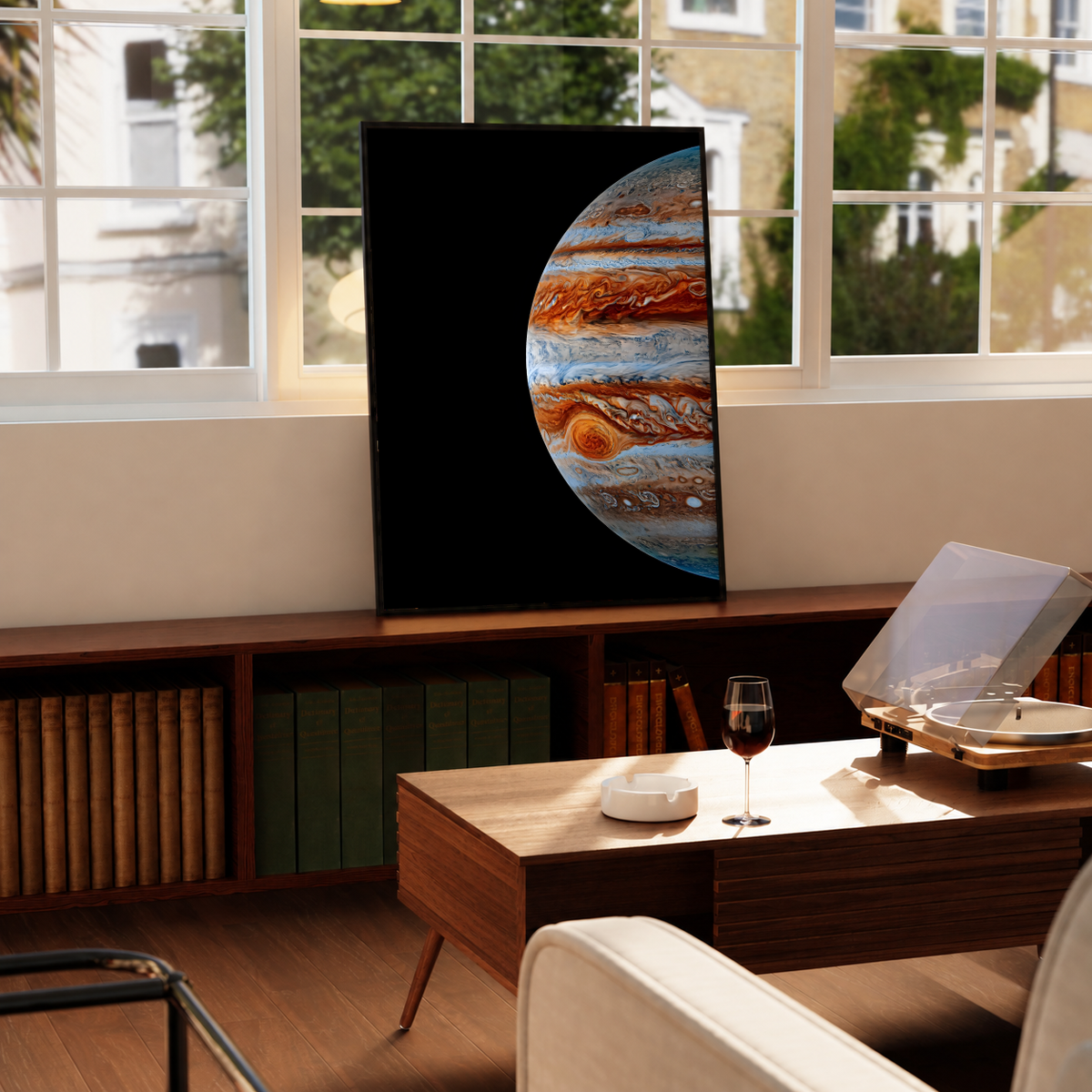 Close-up Jupiter artwork with orange-brown and blue-white cloud bands and the Great Red Spot on black, styled in a black frame above a wood console with books and a record player