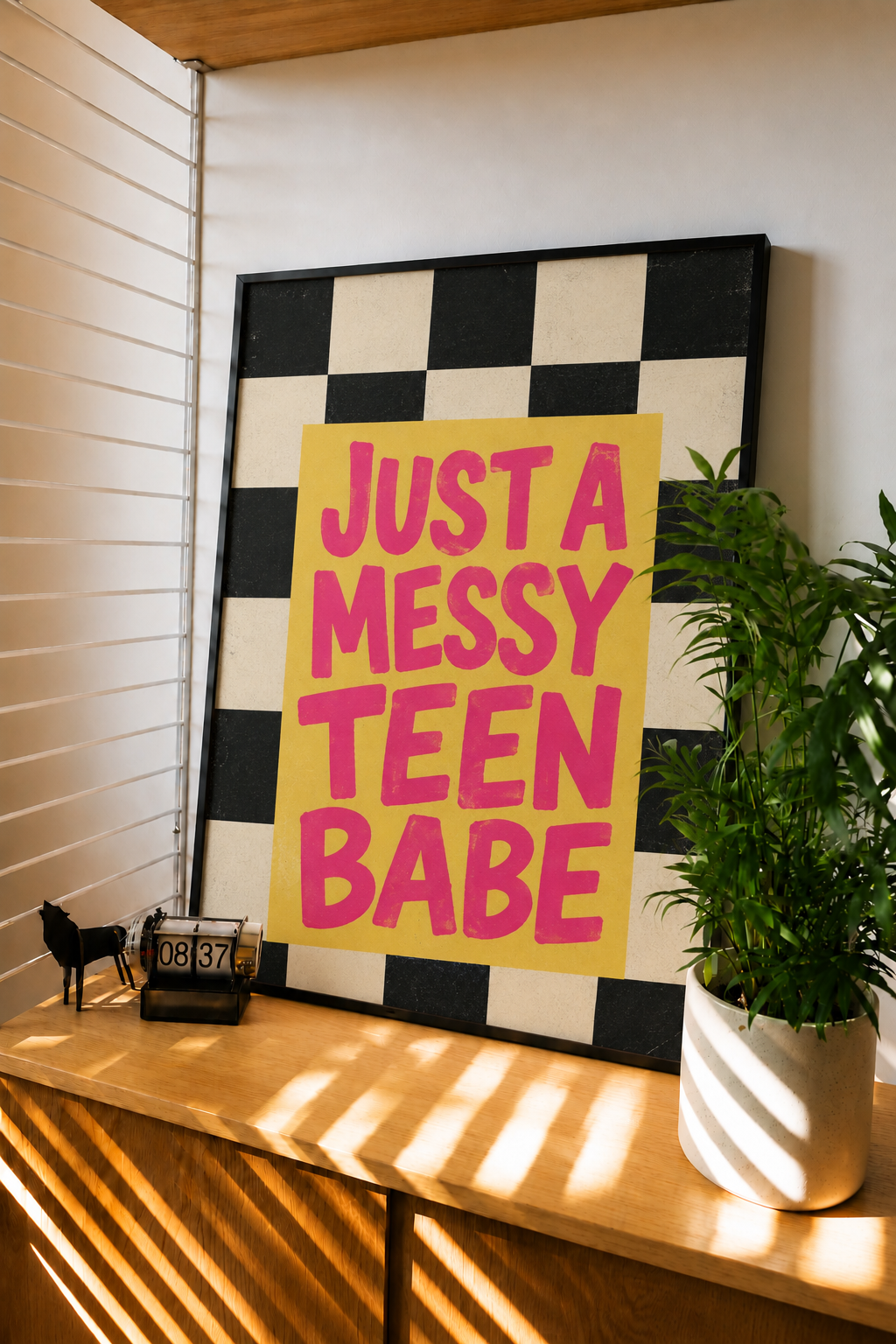 Black-framed wall art with checkered background and pink 'JUST A MESSY TEEN BABE' lettering