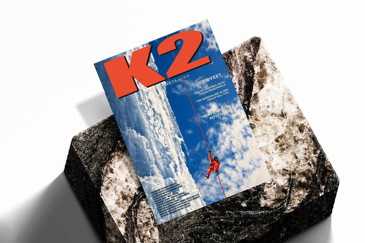 K2 mountaineering poster displayed on a rock surface, featuring a red climber