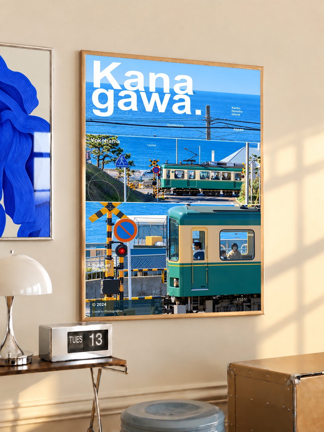 Green coastal train with blue sea and railway crossing in Kanagawa; oak framed print in a desk setting