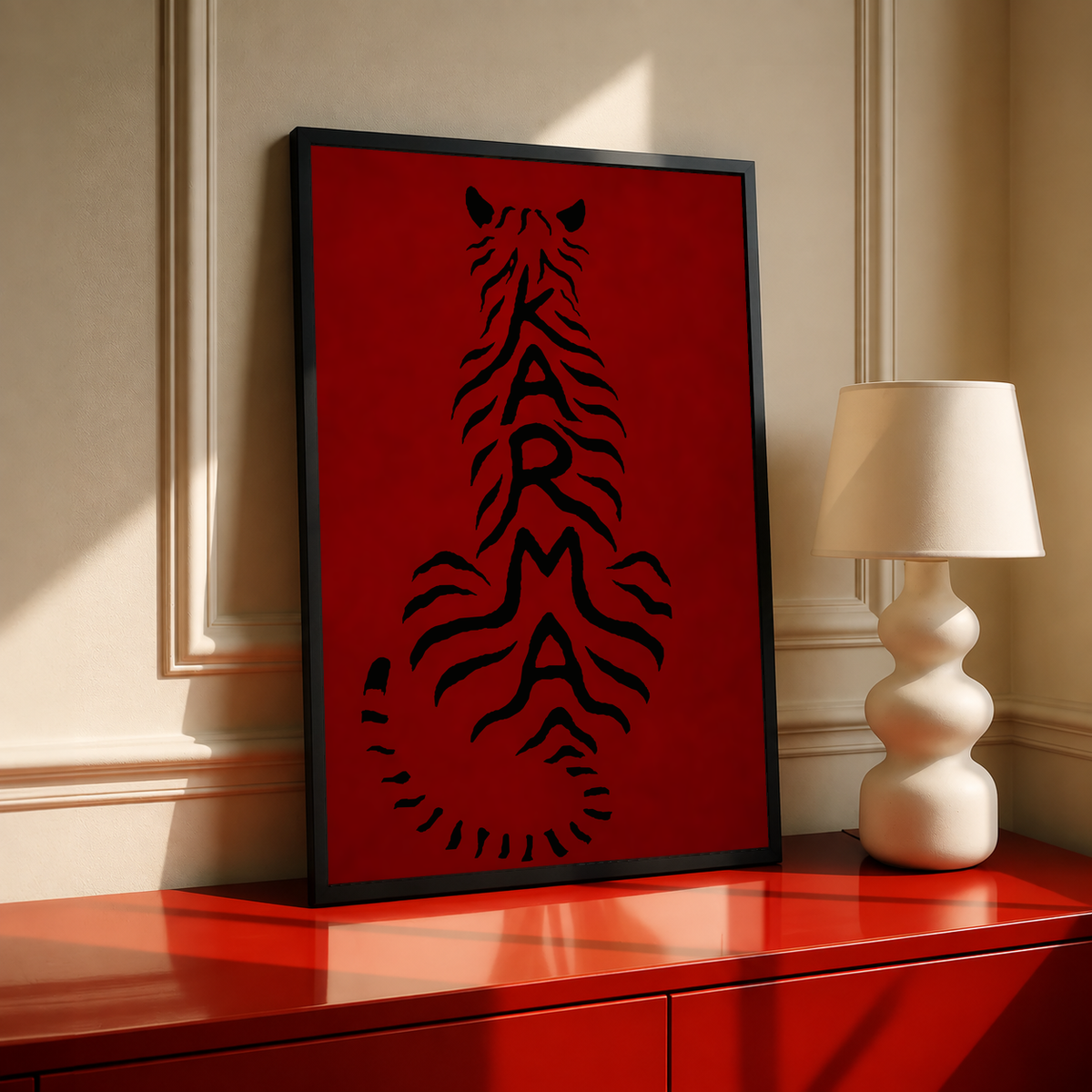 Black-framed deep red poster with black feline typography, leaning on a red cabinet.