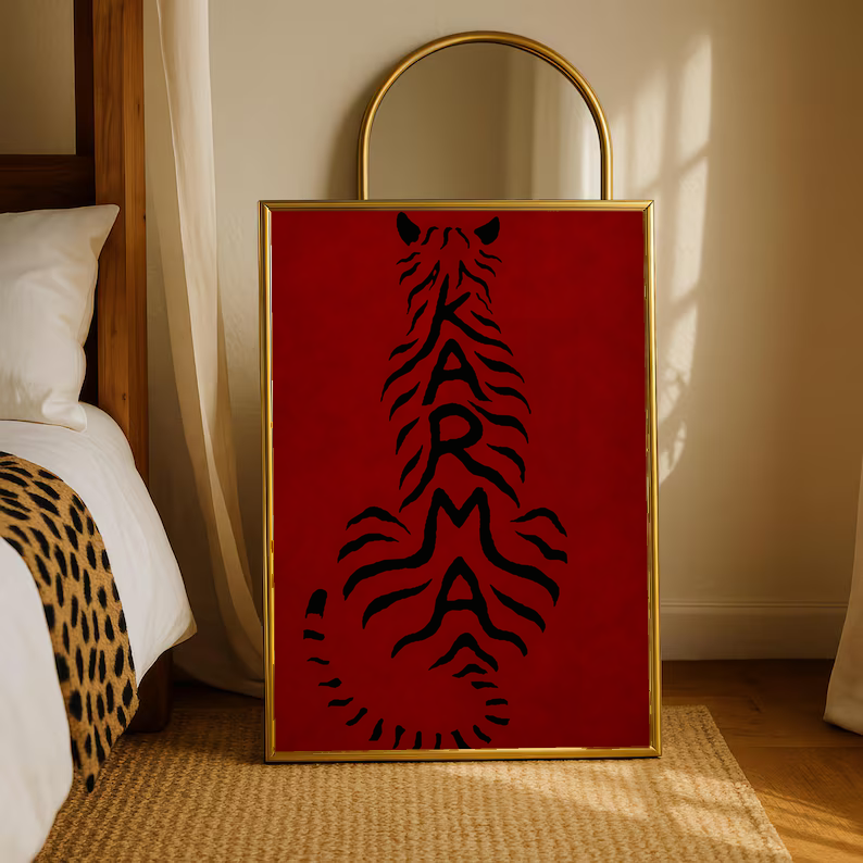 Framed deep red poster with black feline typography, standing on the floor.