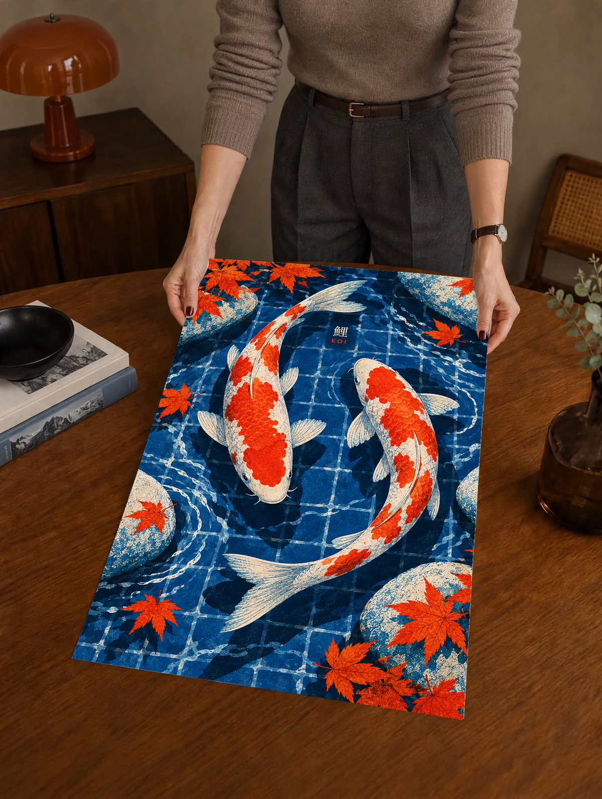 Person holding koi pond art print showing red-and-white koi and autumn maple leaves