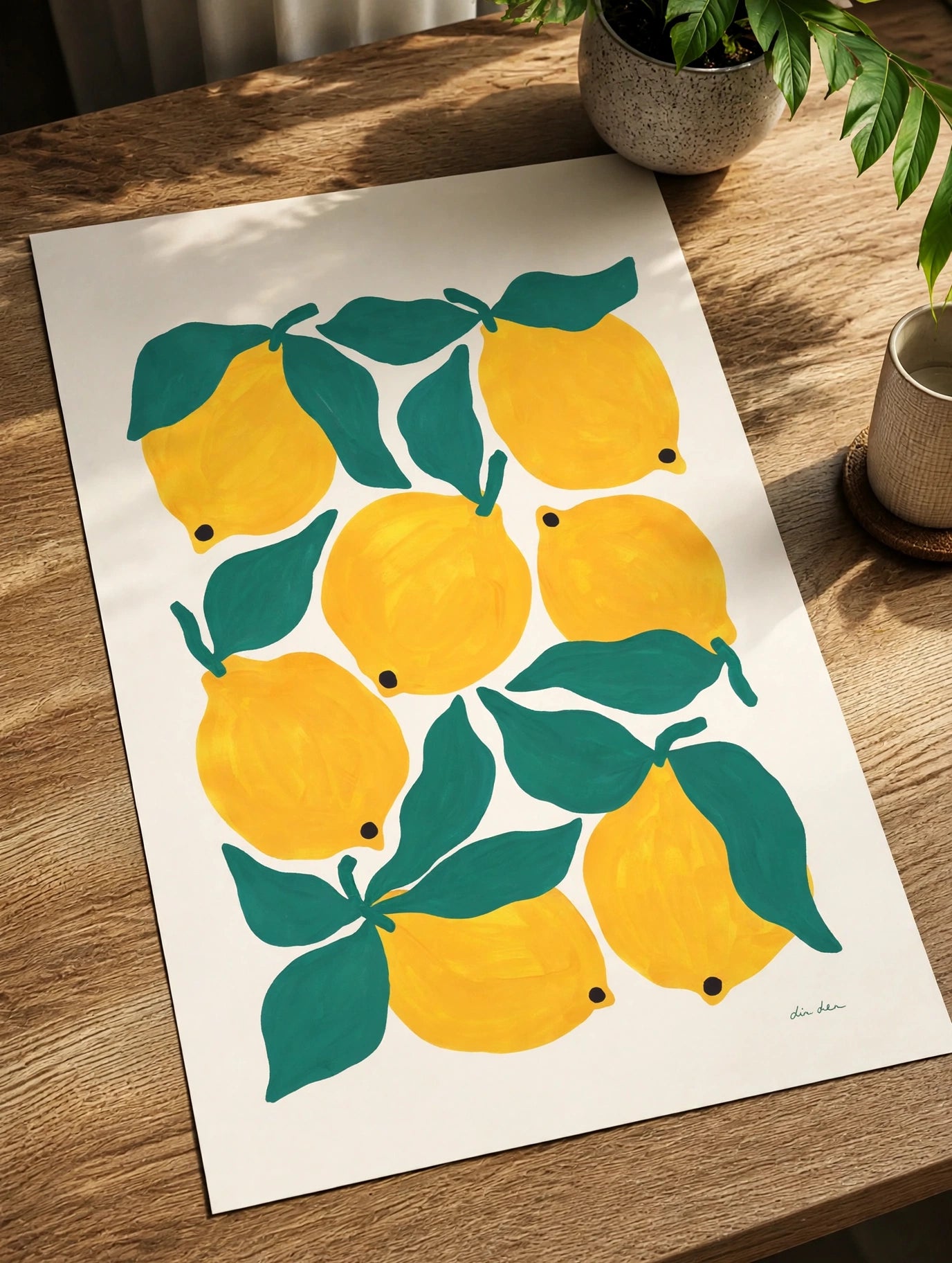 Lemon and green leaf art print on white paper lying on a wooden table