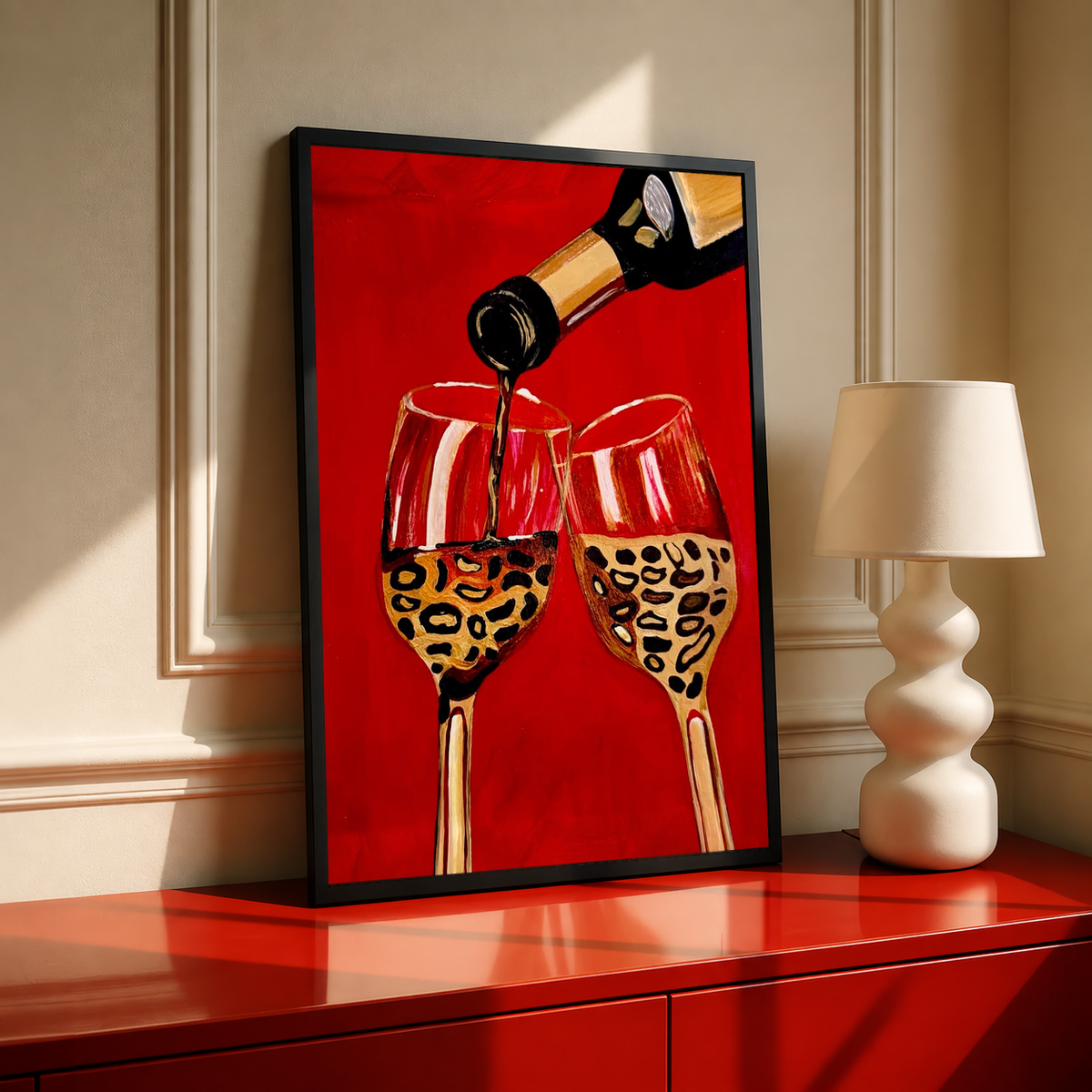 Framed poster of a wine bottle pouring into two leopard-pattern wine glasses on red