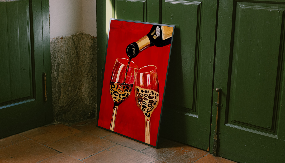Framed wine poster with bottle pouring into two leopard-pattern glasses on red floor