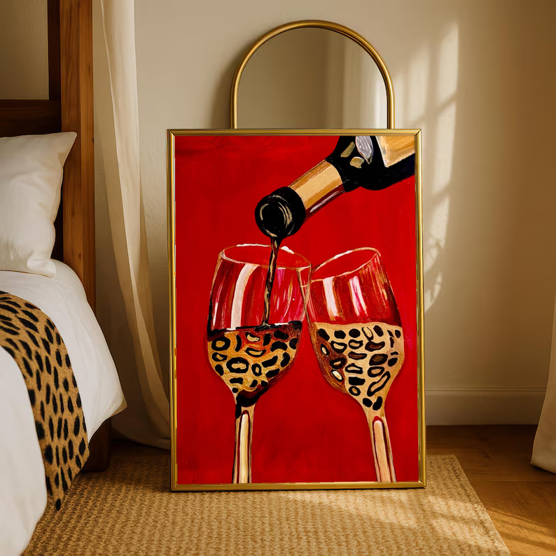 Gold-framed wine poster of bottle pouring into two leopard-pattern glasses on red