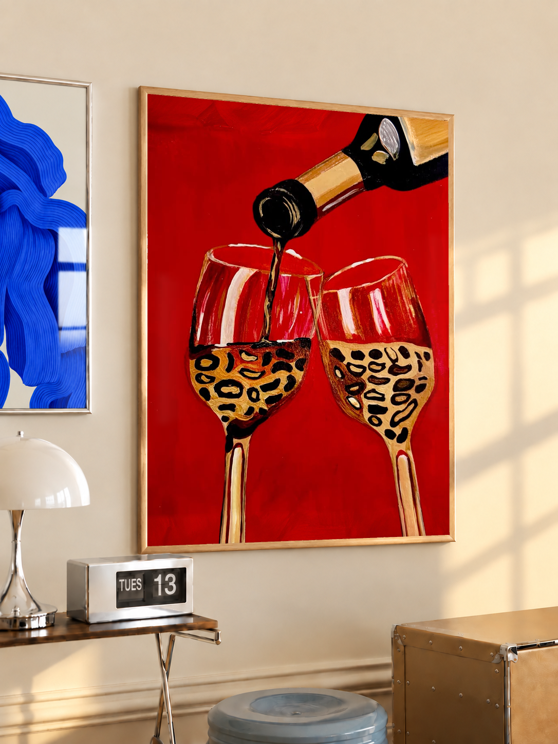Framed wall poster with wine bottle pouring into two leopard-pattern glasses on red