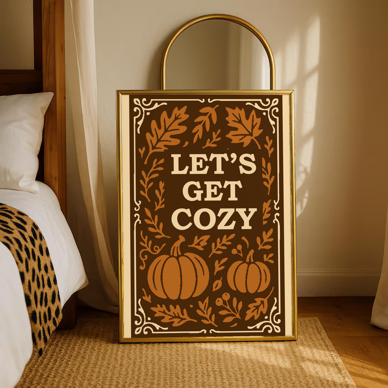 Framed autumn wall poster with cream border featuring brown pumpkins, leaves, and “Let’s Get Cozy”