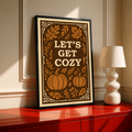 Framed poster with cream border and brown pumpkin-leaf design with “Let’s Get Cozy”