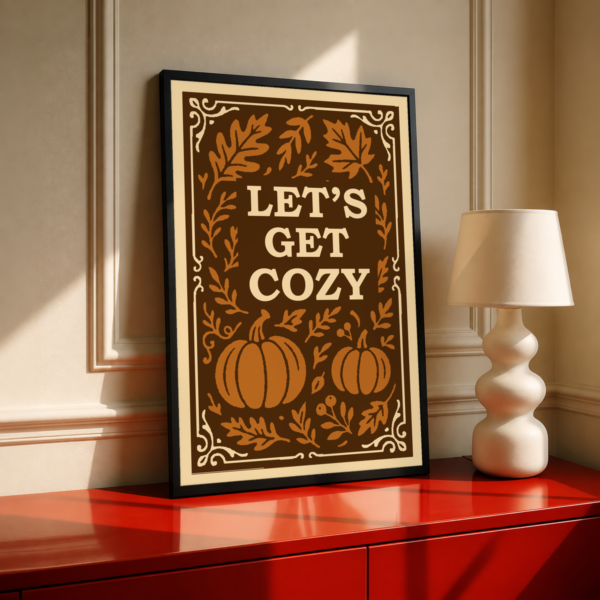 Framed poster with cream border and brown pumpkin-leaf design with “Let’s Get Cozy”