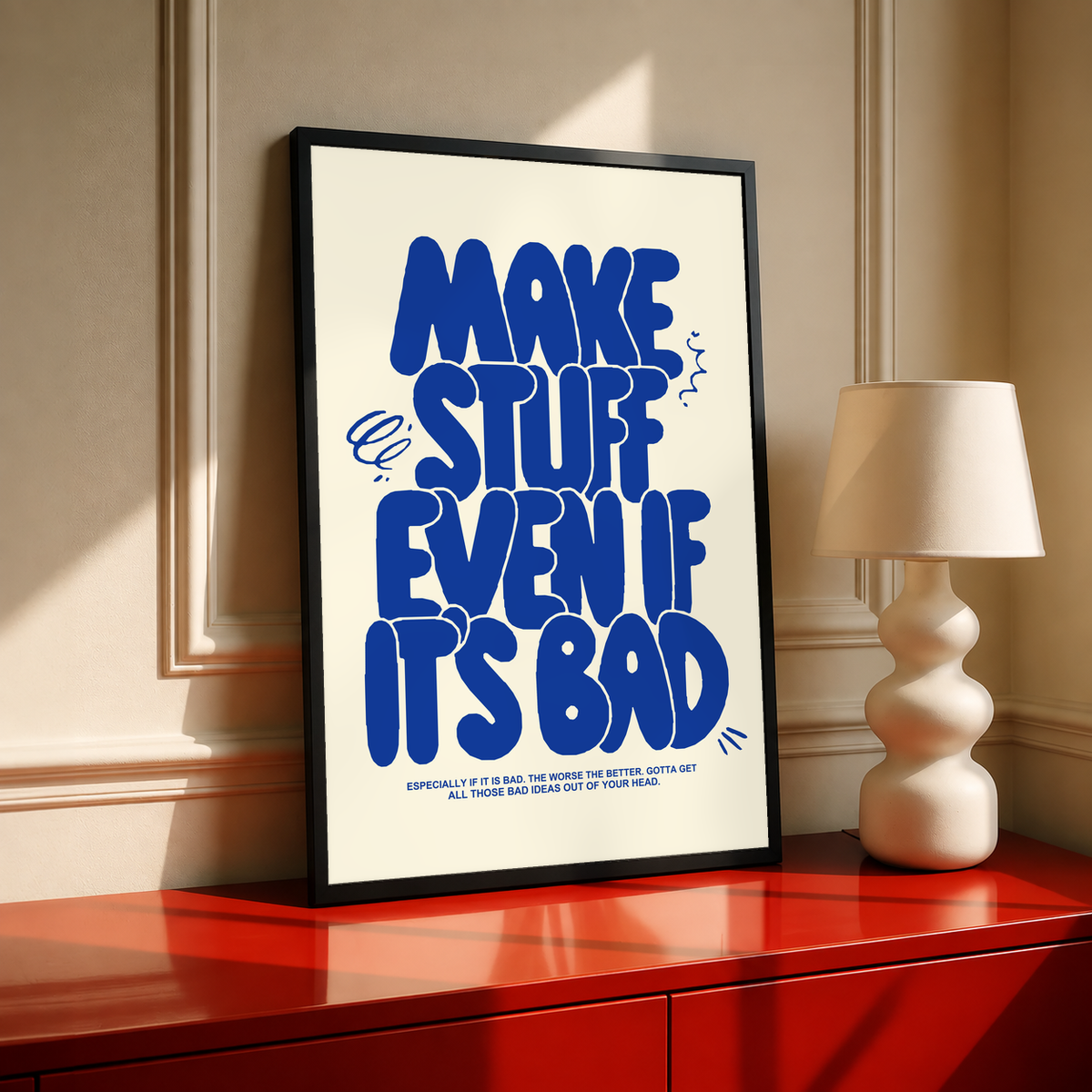 Standing framed cream poster with bold blue “MAKE STUFF EVEN IF IT'S BAD” lettering.