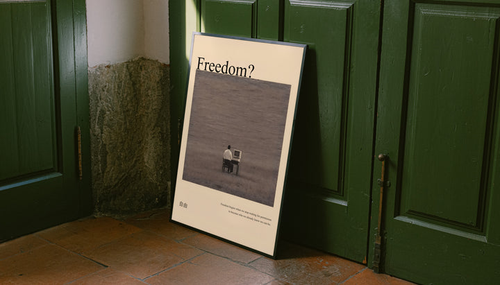 Unframed art poster leaning on green doors, “Freedom?” title and man at desk