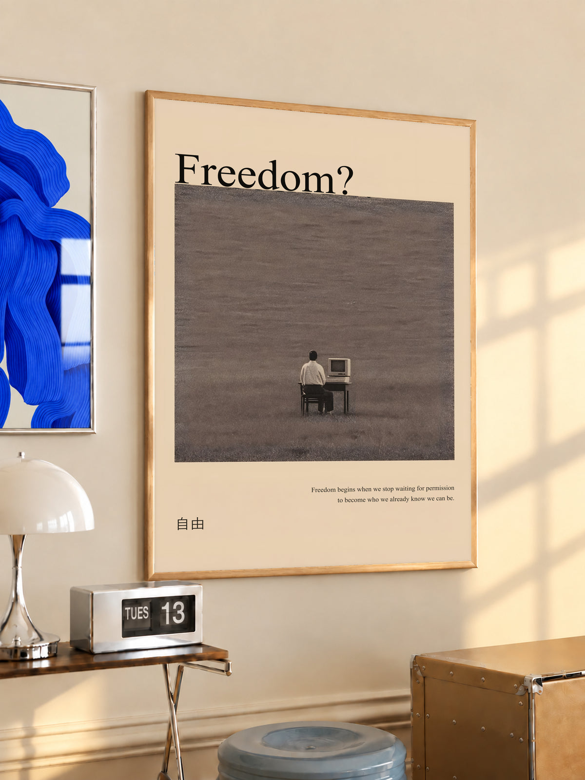 Beige framed art poster featuring “Freedom?” title and a small man at desk