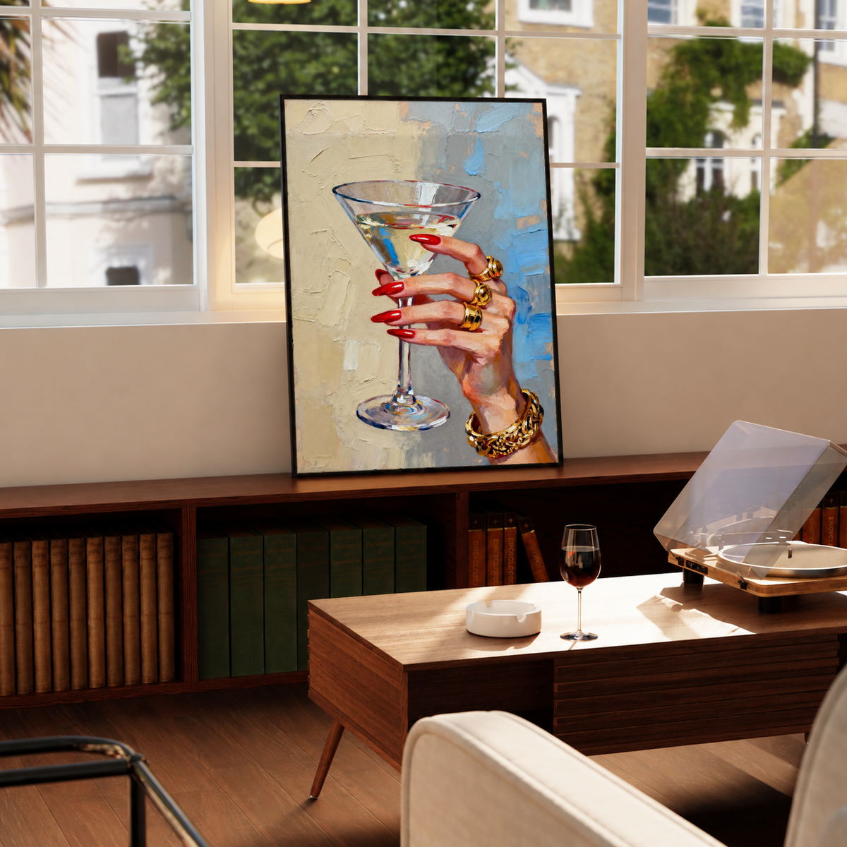 Black-framed martini hand print artwork with red nails, gold rings, and painterly blue