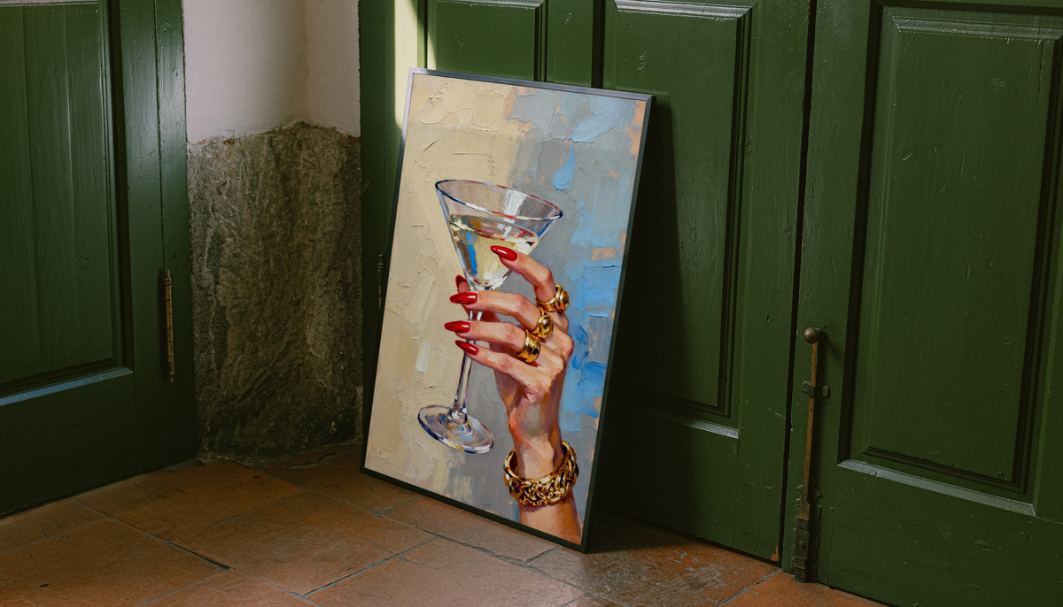 Framed hand print artwork of a martini glass with red nails and gold rings