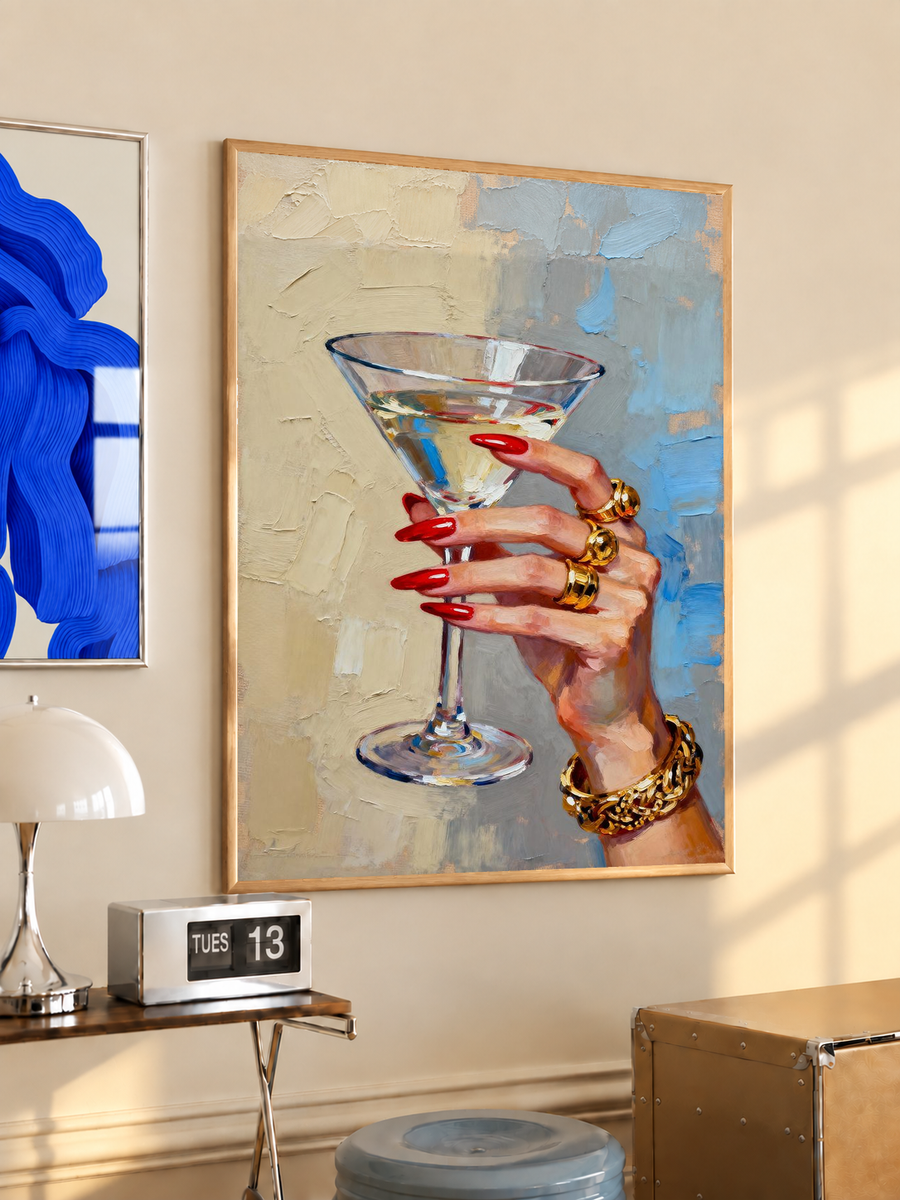Framed hand print artwork of martini glass with red nails and gold rings, painterly blue