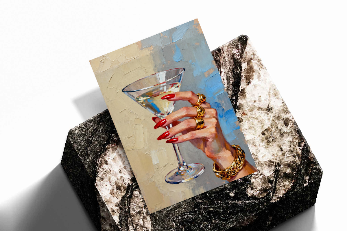 Tilted hand print artwork of martini glass with red nails and gold rings on blue