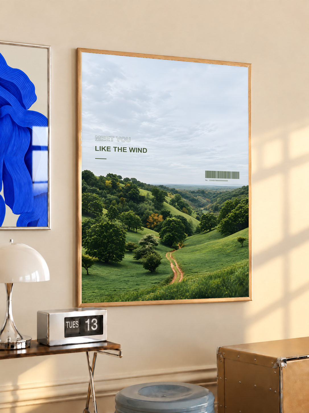 Green valley and winding path beneath Meet You Like the Wind lettering; oak framed print in a desk setting
