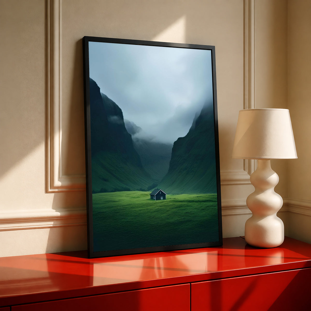 Dark-framed mountain valley artwork with misty blue cliffs, green grass, and small cabin