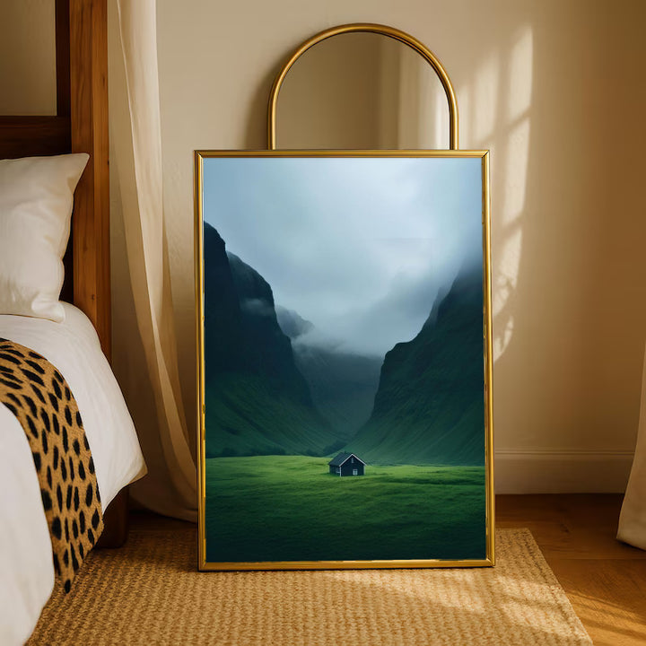 Gold-framed mountain valley artwork with misty blue peaks, green hills, and small cabin