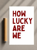Romantic quote print with red “HOW LUCKY ARE WE” text on white sheet