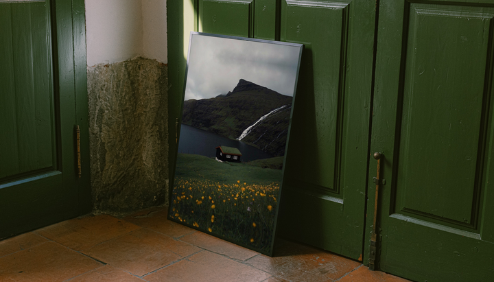 Moody Lake Cabin Wall Art shown as a canvas leaning beside green panels on a wooden floor.