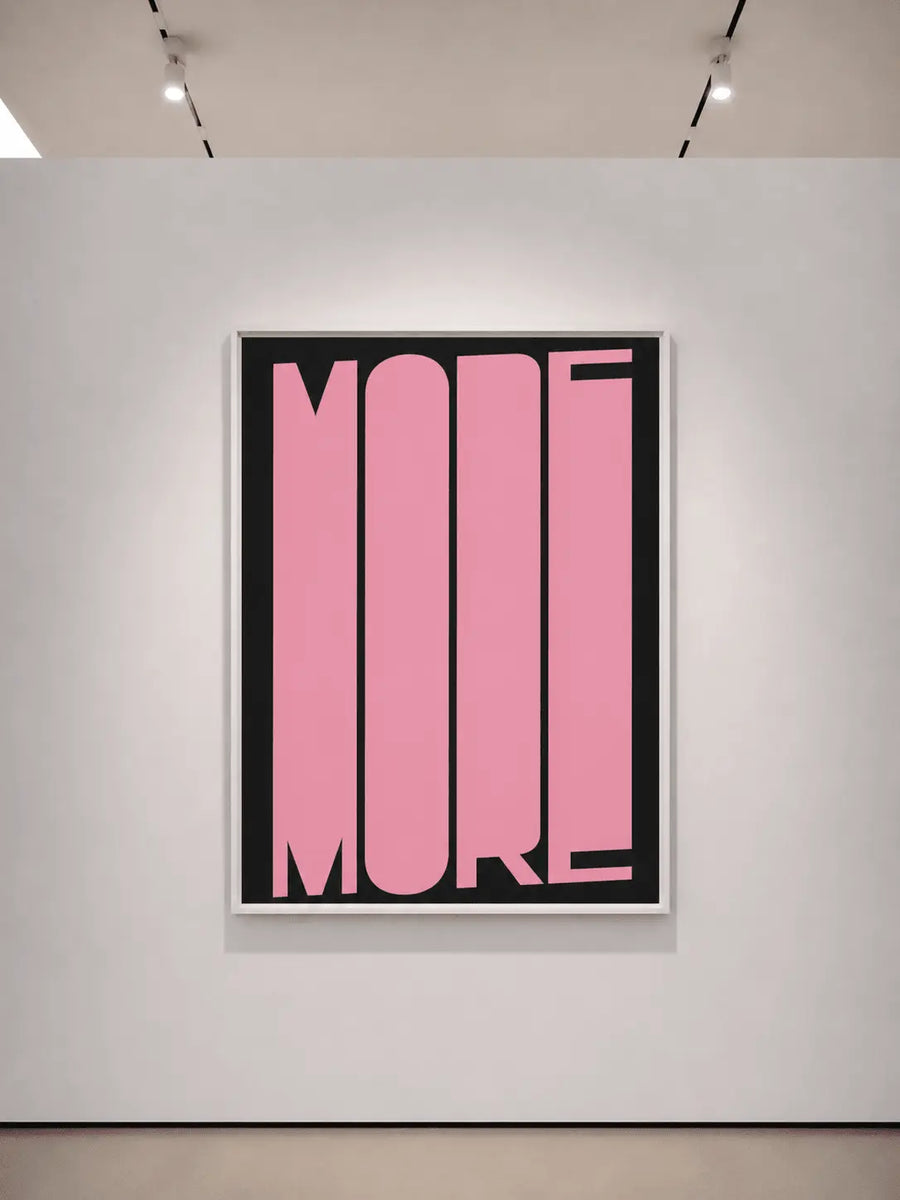 Framed typography art print with pink 'MORE' on black background, light gray frame