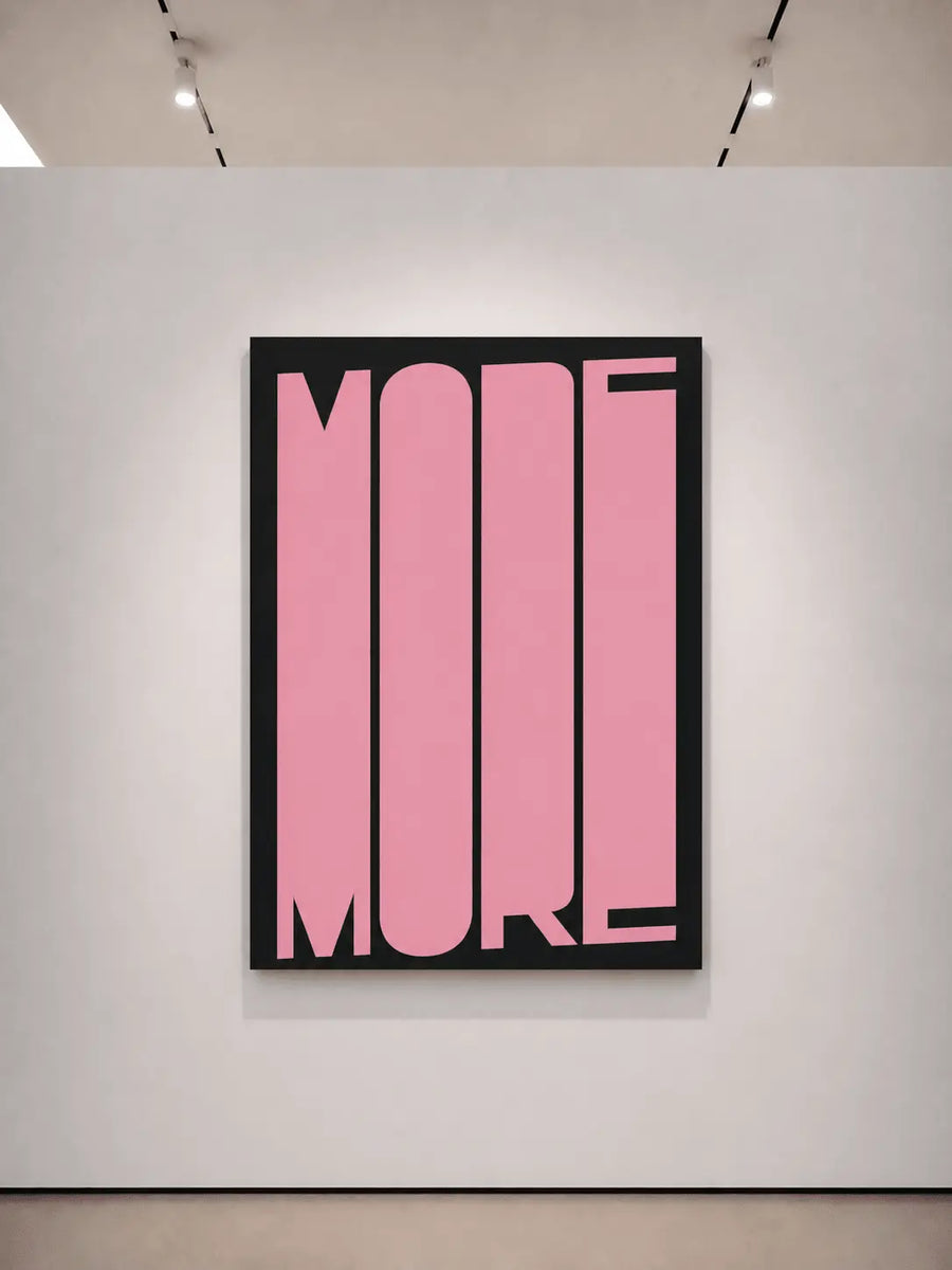 Framed typography art print with pink 'MORE' on black background, dark frame